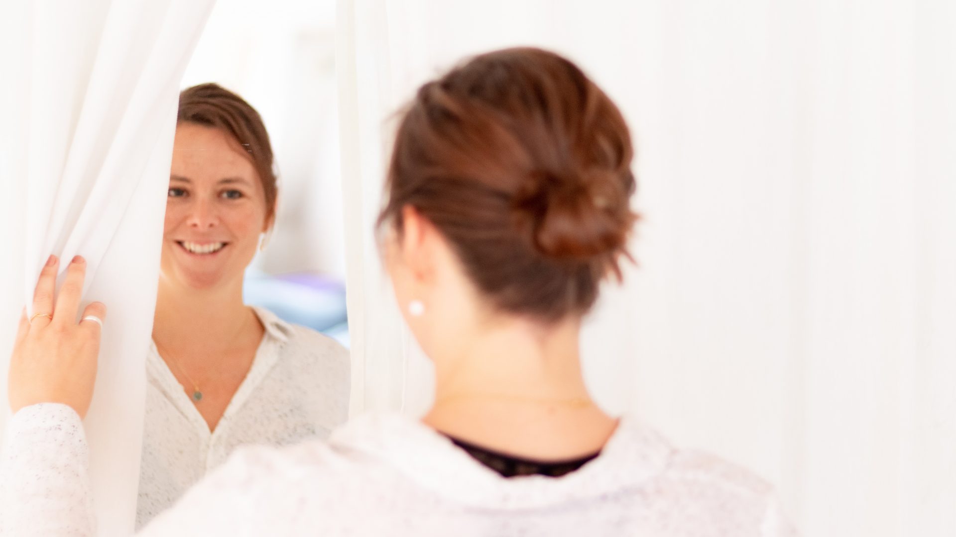 En kvinder der smiler og ser på sig selv i et spejl