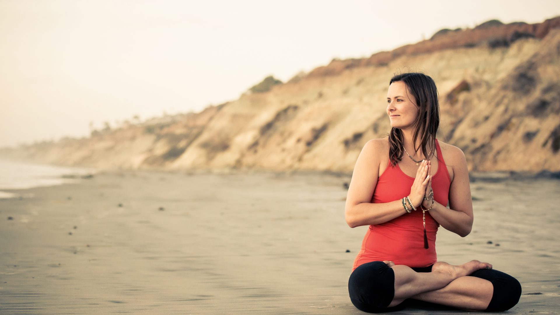 Kvinde der sidder på en strand og mediterer