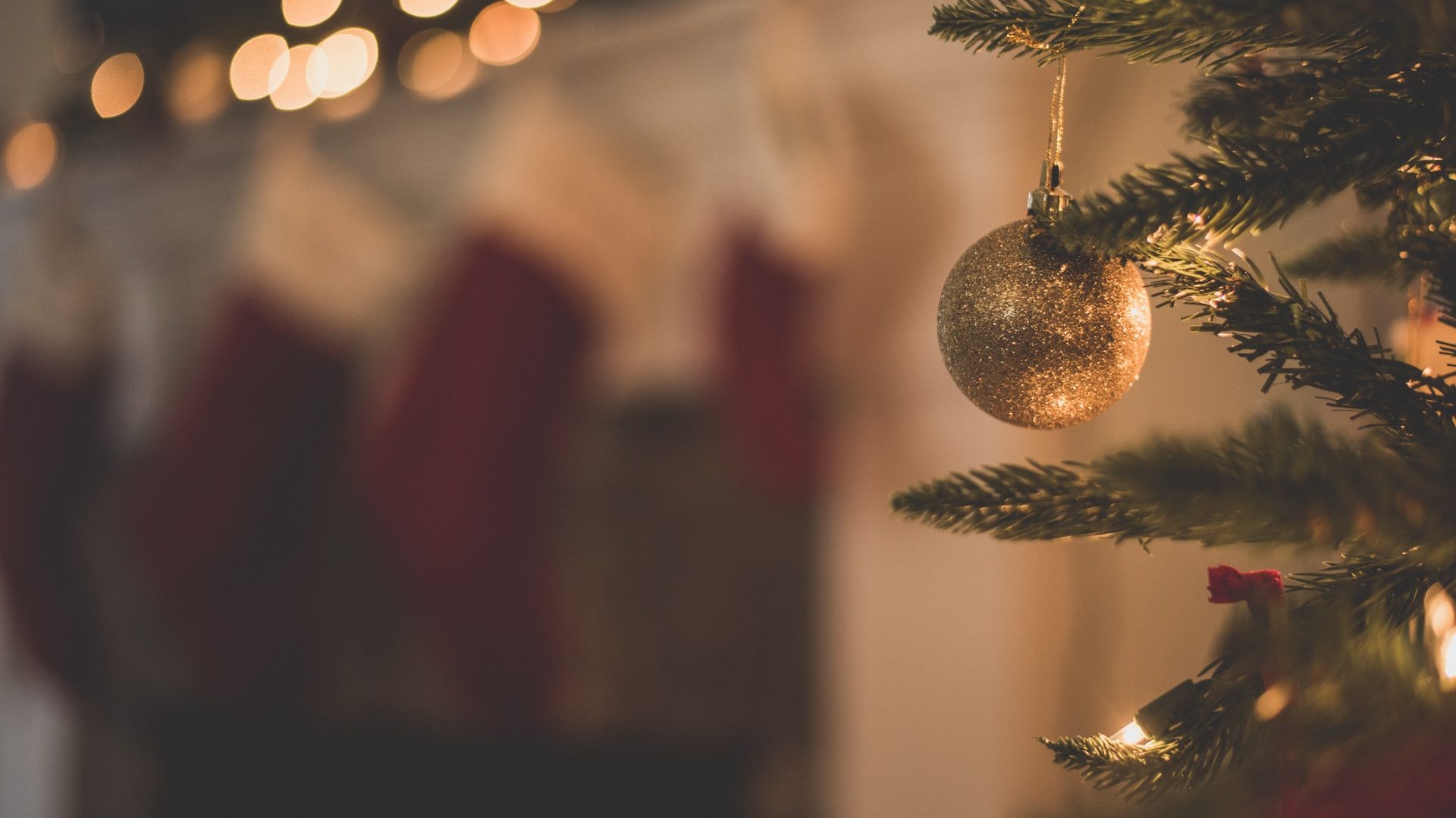 Guld julekugle med glimmer hængende fra et juletræ