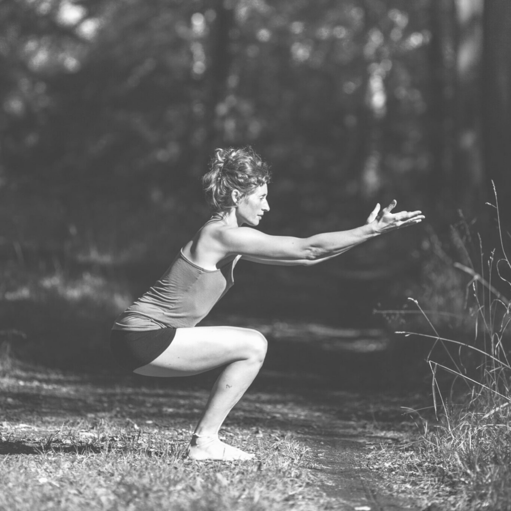 Kvinde der dyrke yoga i skov fra NAYA kropterapeutisk yoga uddannelse